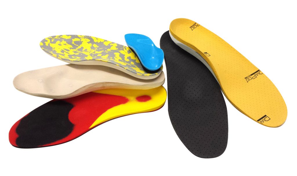 Varie solette colorate per scarpe su sfondo bianco.