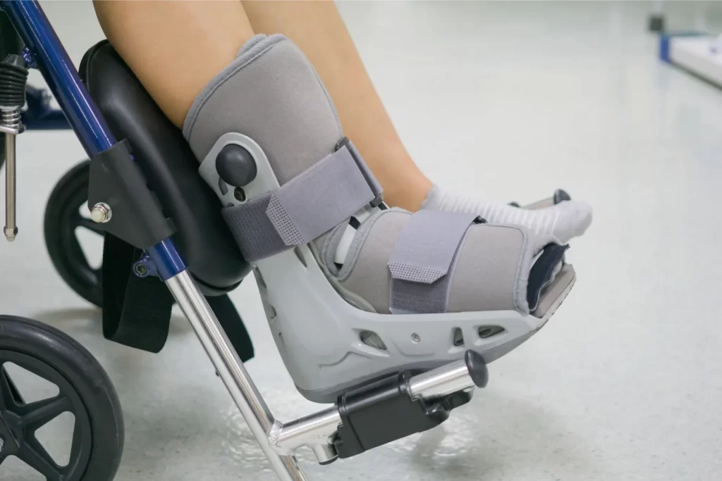 Piedi in tutori su sedia a rotelle.